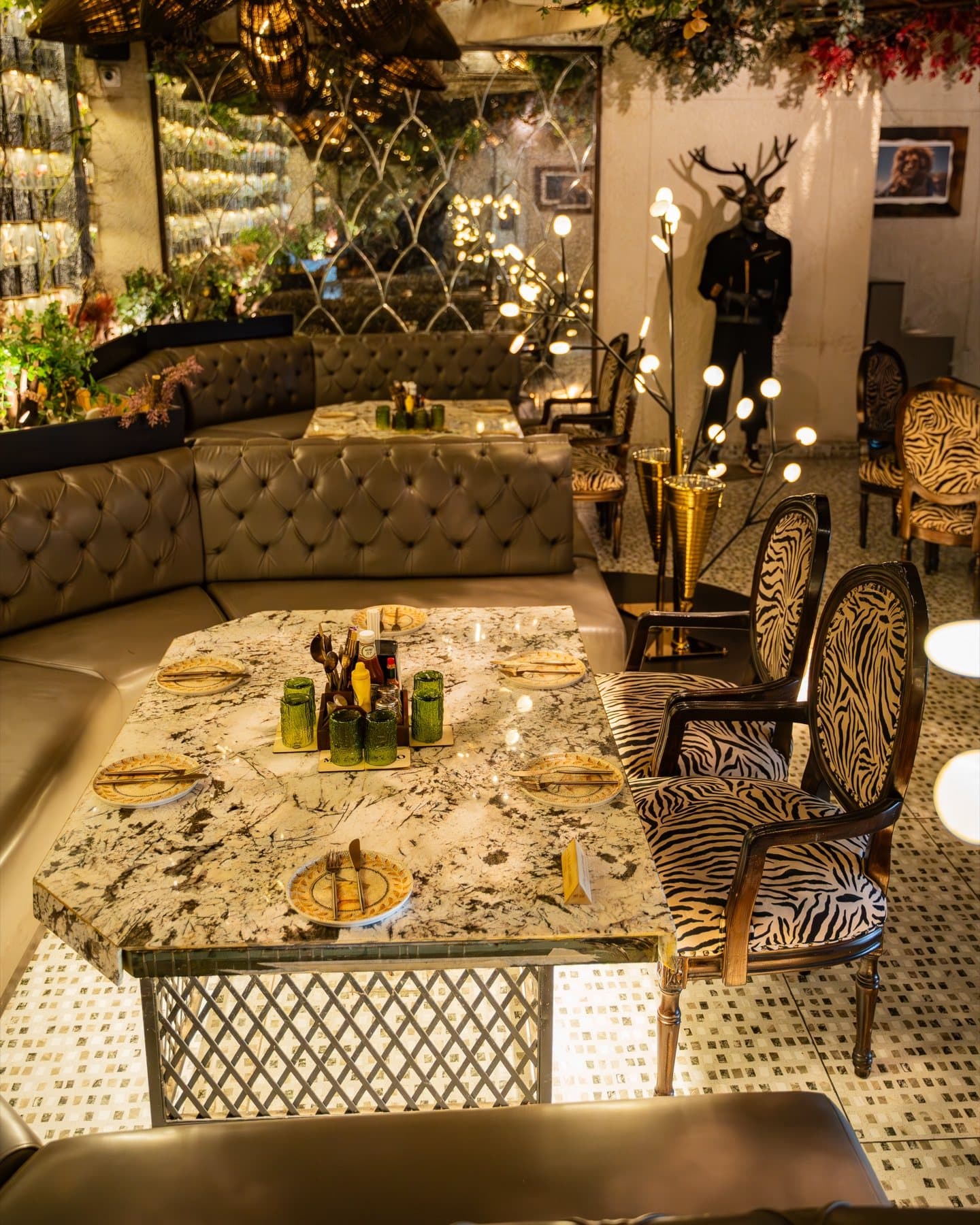 Curved banquette wrapped in warm light beneath mirrors and botanicals