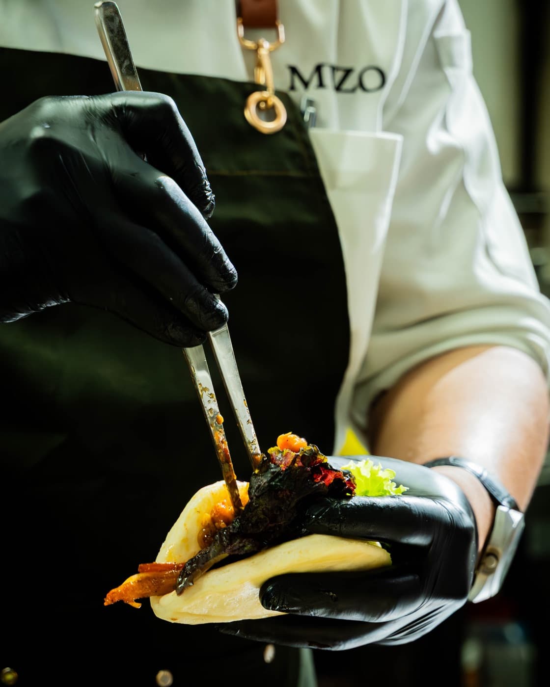 Chef finishing a bao with brass MEZO keyring on the apron