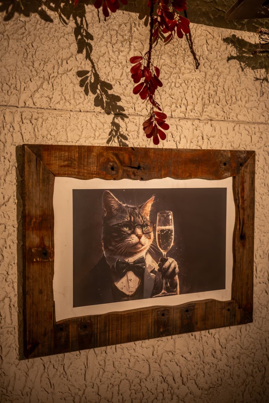 Framed portrait of a cat in a tuxedo raising a champagne coupe