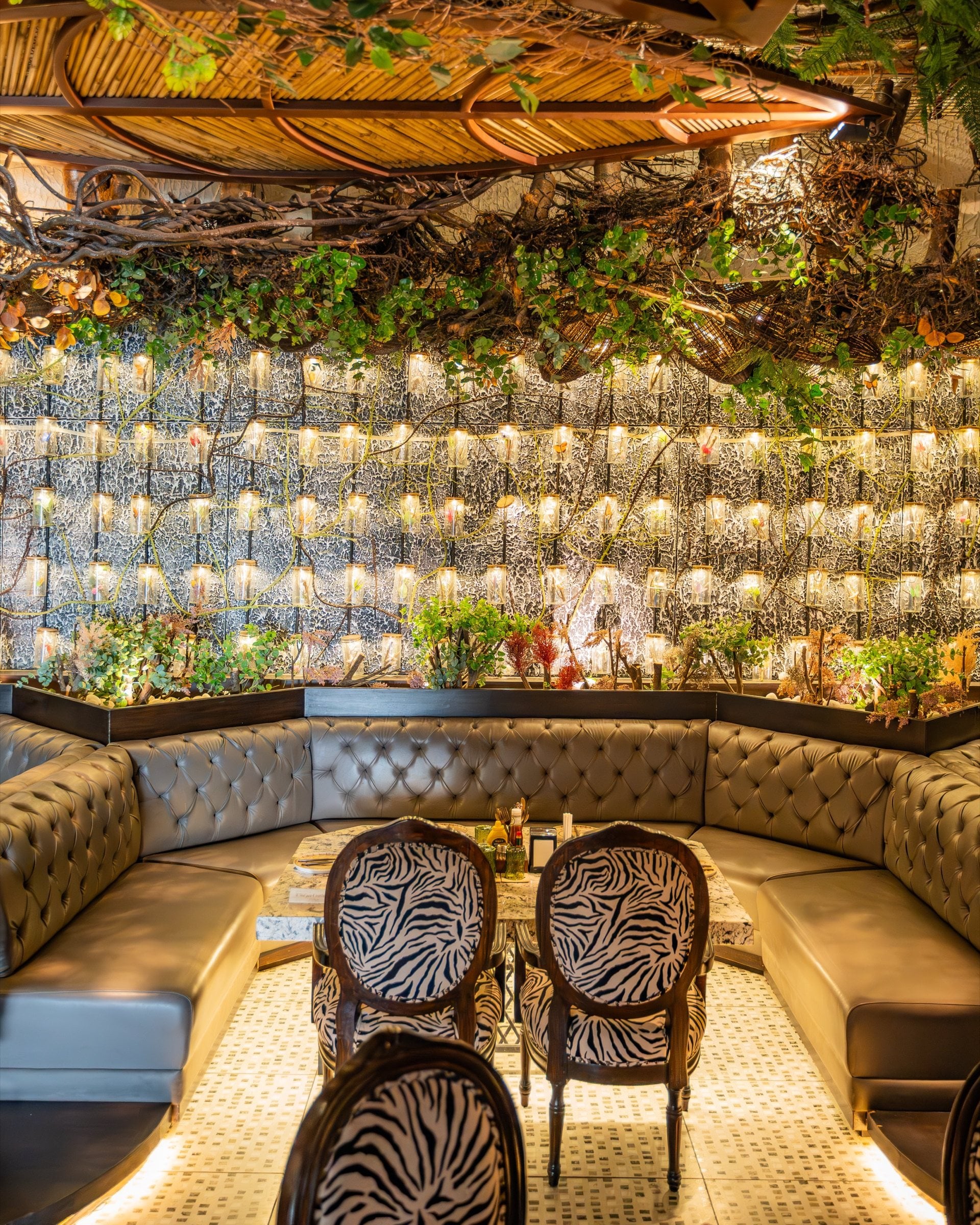 MEZO dining room at night — curved banquettes beneath a carved timber canopy and a wall of glowing amber bottles